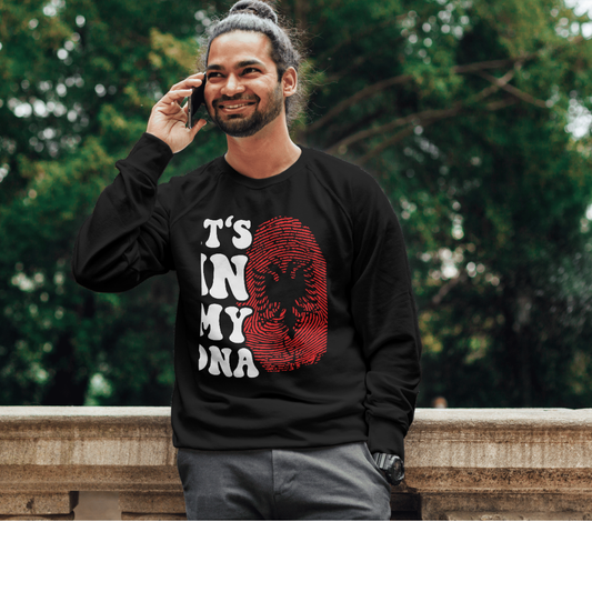 Man wearing a black sweatshirt with Albanian graphic design outdoors